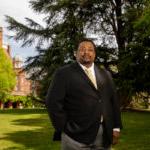 Charles Gibson III poses in front of Main Hall on campus