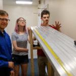 Gregory Wietrzykowski '26, Alaina Snider '27, and professor Peter Sheldon roll a toy car down a ramp as part of their summer research